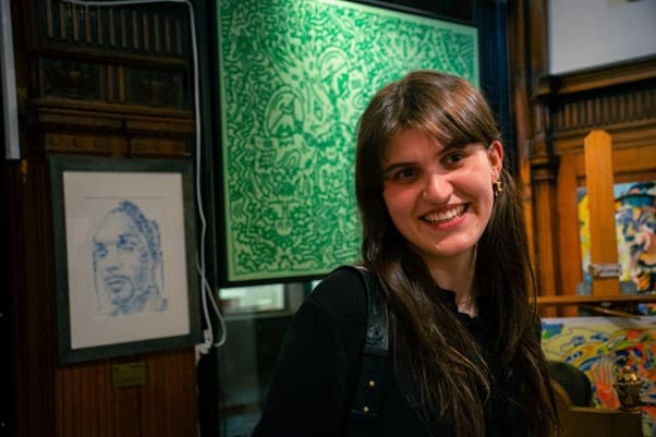 Volunteer in art gallery surrounded by colorful artwork